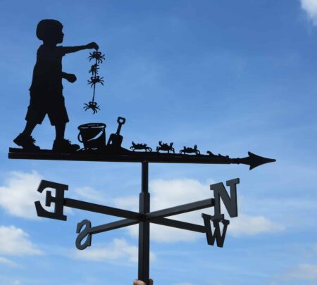 a weathervane design of a child crabbing at the seaside against a light blue sky