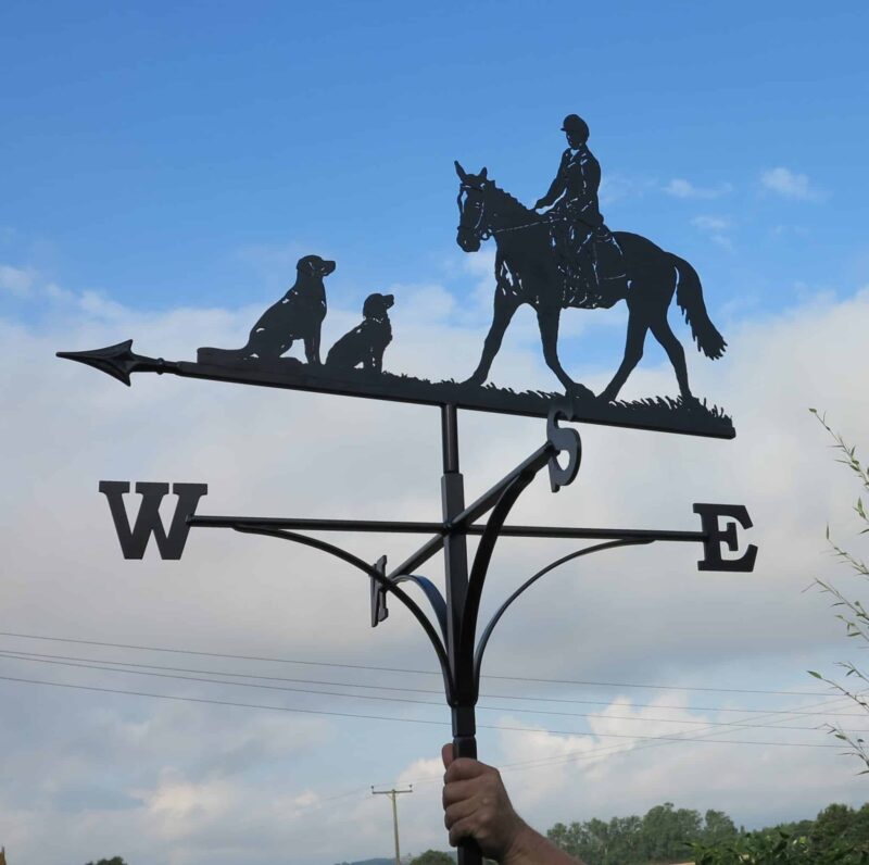 a black Dressage Horse Women And Dogs Weathervane against a blue sky in kent