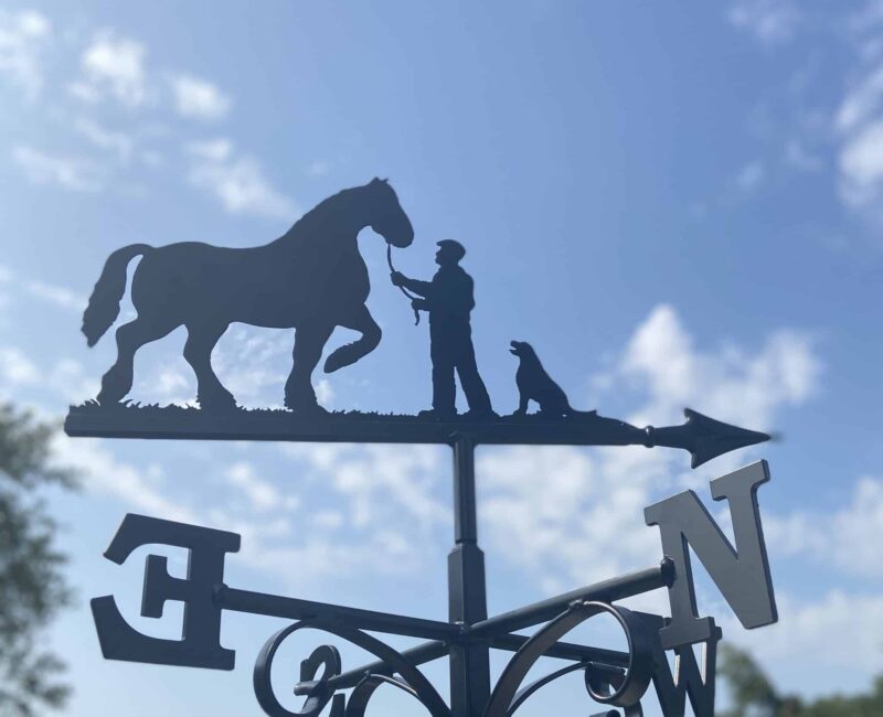 Shire Horse, Man & Labrador Weathervane against a blue sky with fluffy white clouds