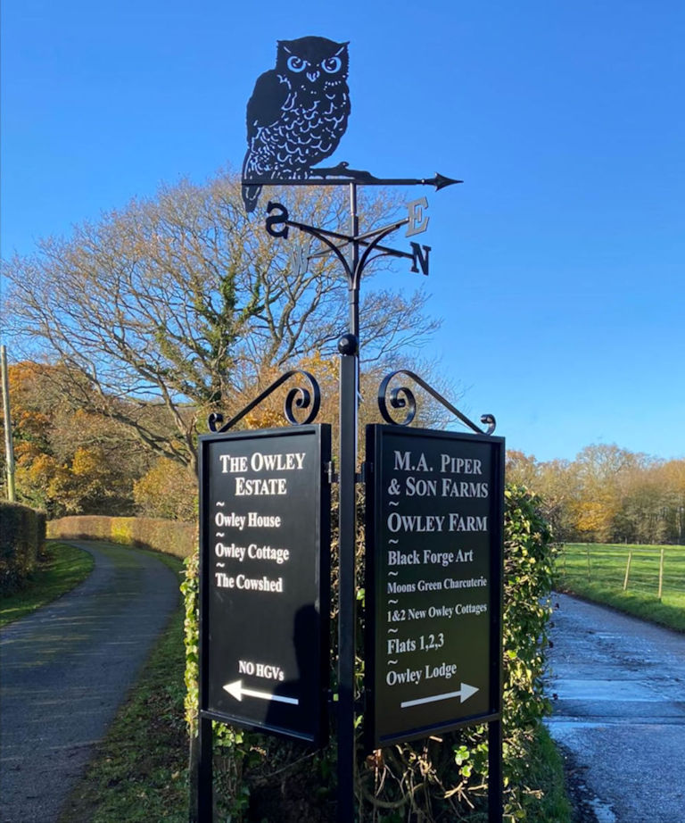 Black Forge Art road entrance direction sign with weathervane